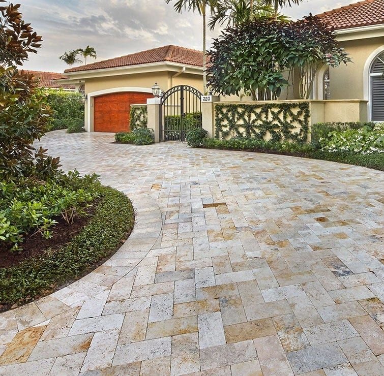 Travertine paver driveway leading to a gated entry