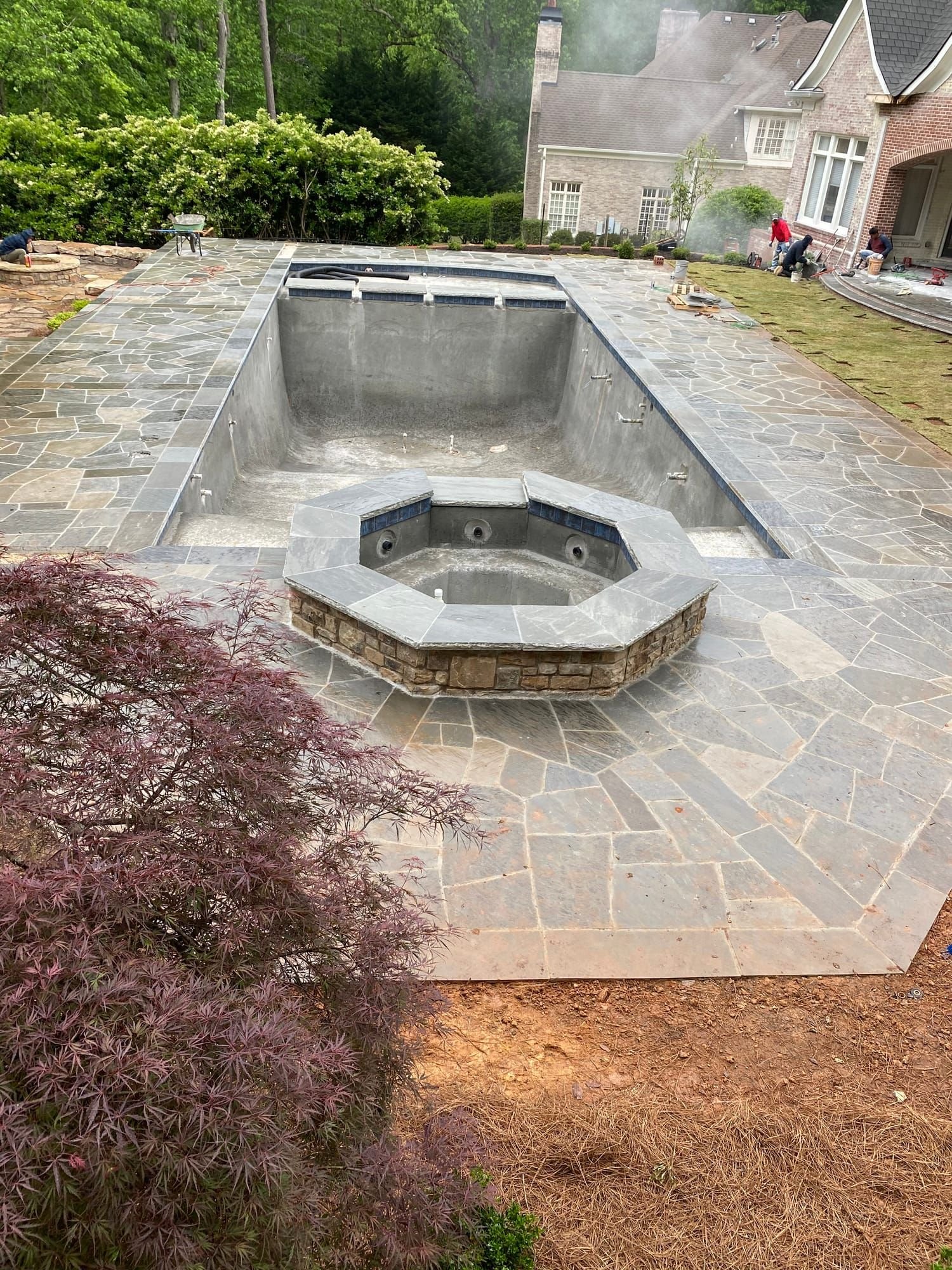 Flagstone pool deck with a built-in fire pit