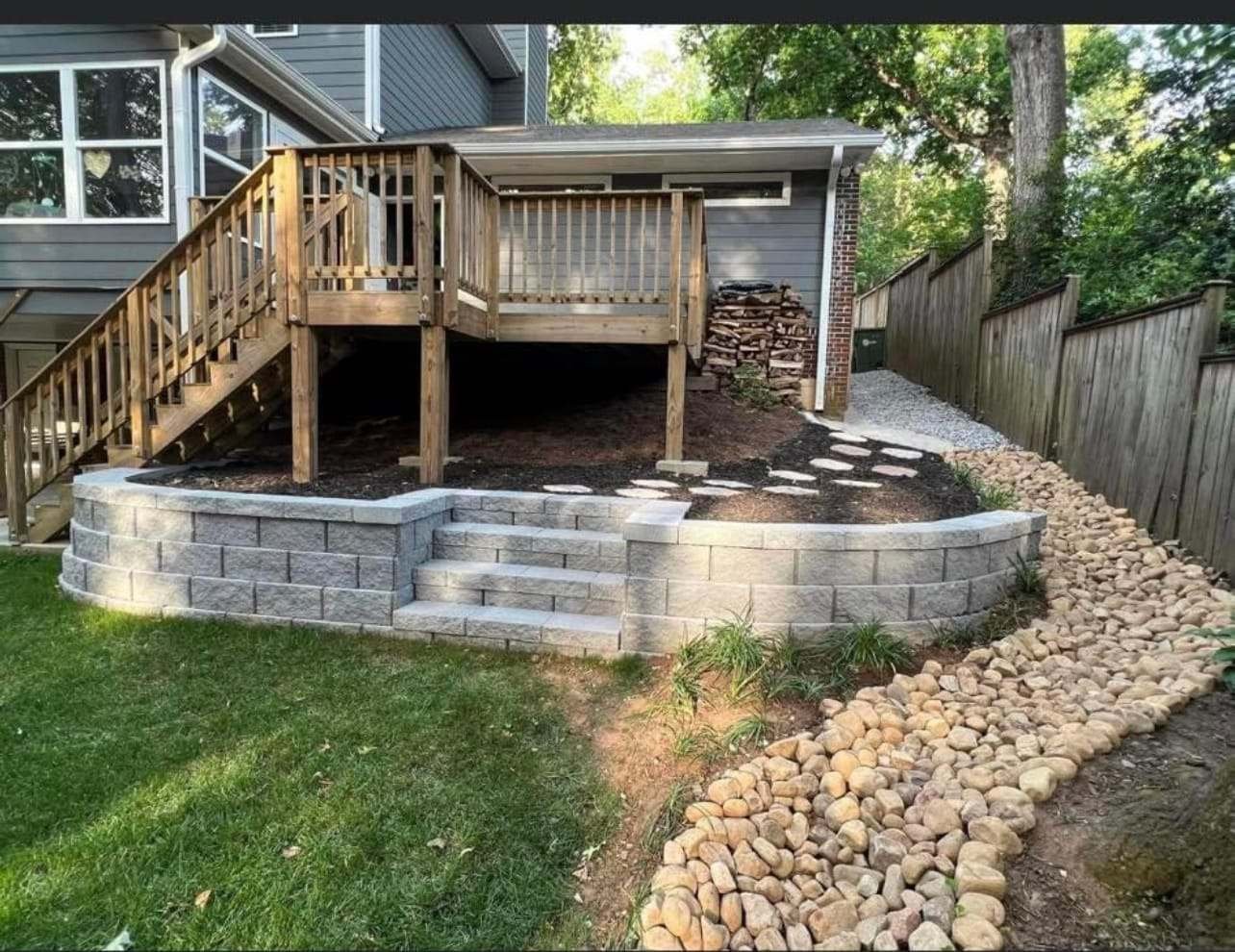 Stone retaining wall with river rock below a deck